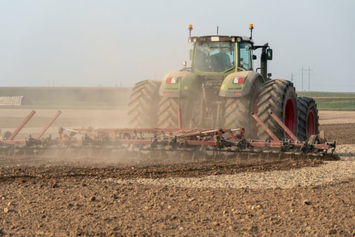 large tractor pulling a plow through soil